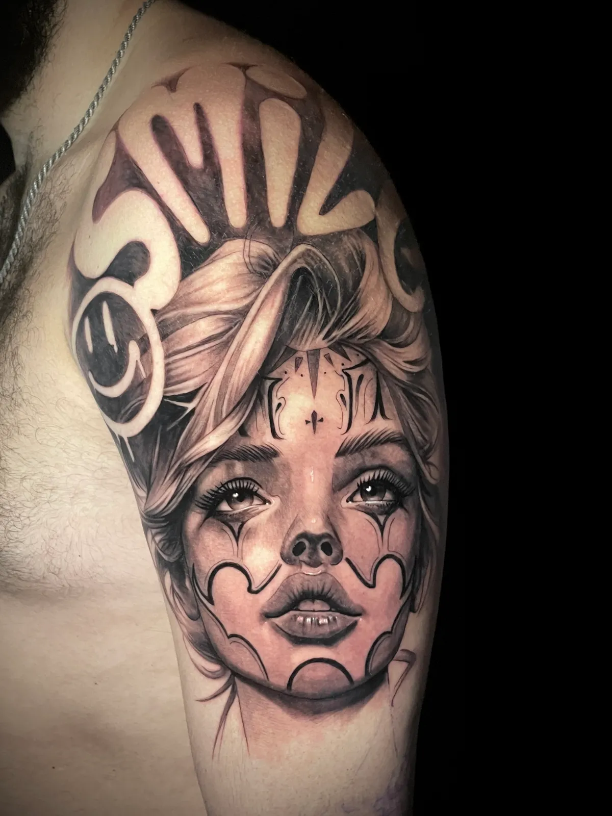 Black and grey Chicano style woman portrait with smile lettering half sleeve tattoo by Paul Michael Andras