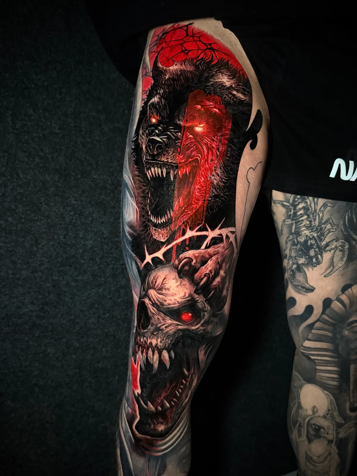 Black and grey realism demonic bear and skull tattoo with red glow accents on full sleeve by Andras Tattoo