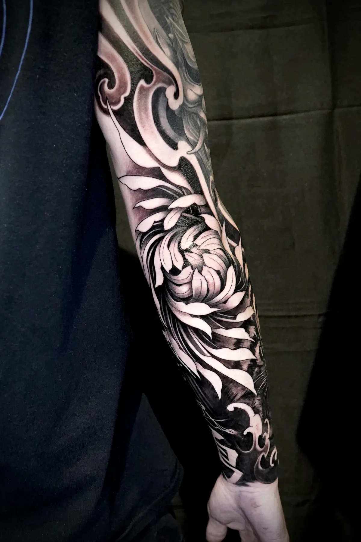 Black and grey Japanese chrysanthemum flower full forearm sleeve tattoo with bold contrast by Andras Tattoo
