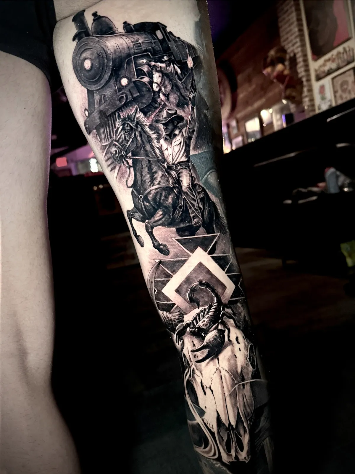 Black and grey realism Western cowboy on horseback with steam train and bull skull full sleeve tattoo by Andras Tattoo