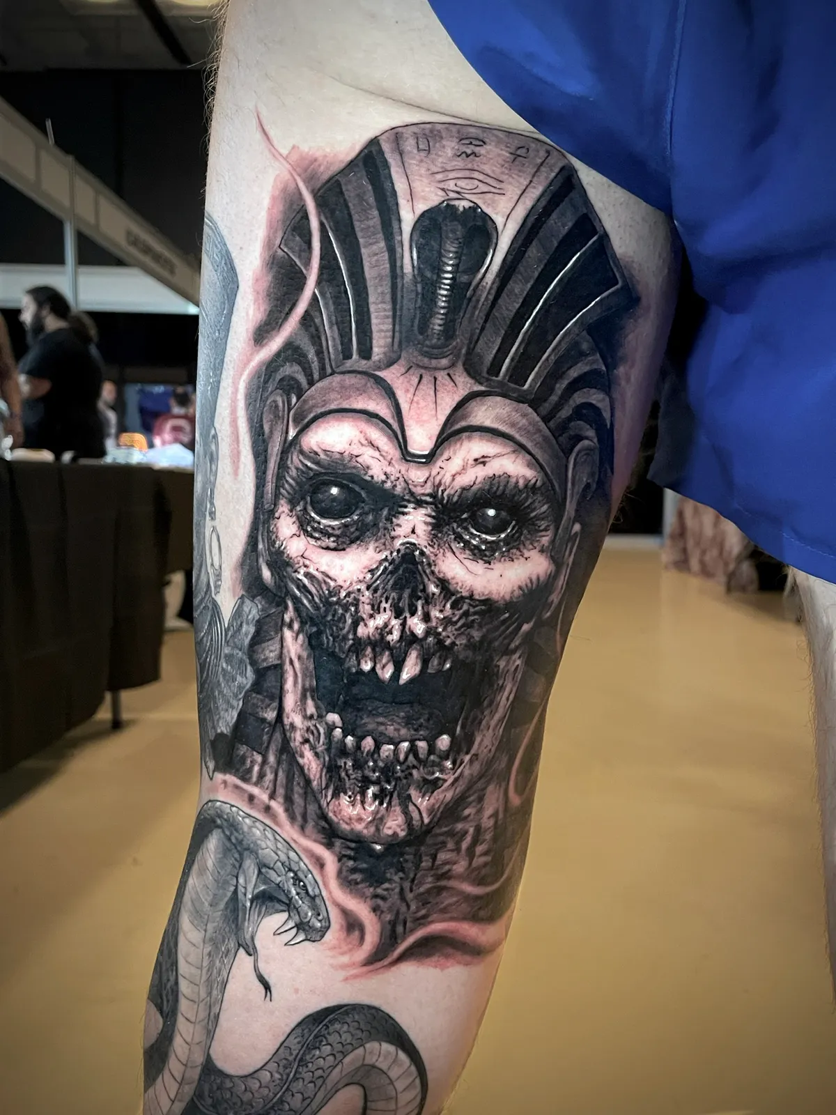 Black and grey realism dark Egyptian pharaoh skull with cobra snake upper arm tattoo by Paul Michael Andras