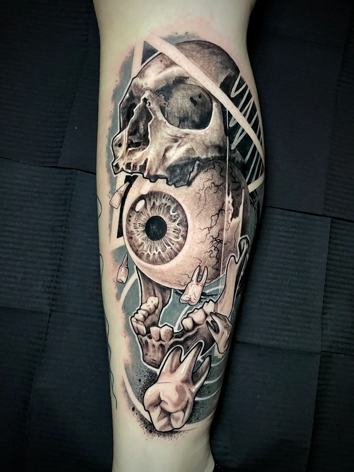 Black and grey realism skull with clock face and eyeball held by skeleton hand calf tattoo by Paul Michael Andras